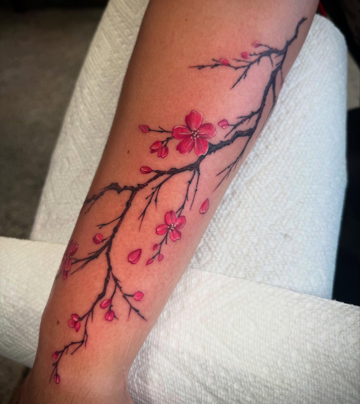 Cherry blossom branch in soft pink colour realism, running down a forearm.